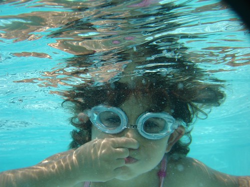 Child wearing goggles learning to swim.