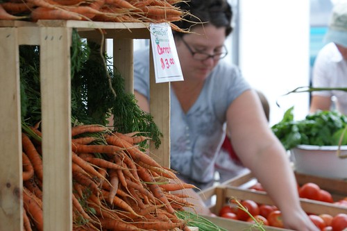 Woman working a stall at a farmers market.