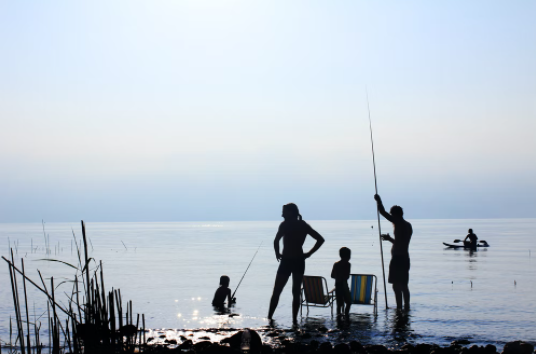 Picture of a family fishing off the shore of a beach.