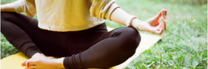 Image of a woman in a yoga pose on a mat in a grass field.