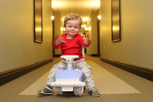 Image of a small child riding a scooter in a hotel hallway.