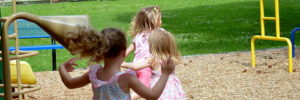 3 small children running in a playground.