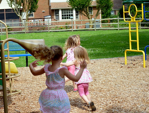 3 small children running in a playground.