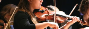 Shot of a woman playing the violin in an orchestra.