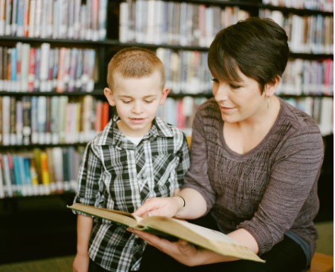 Small child and parent reading a book at a library in Cedar Park, TX.