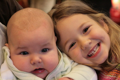 A small girl hugging her new baby sibling.