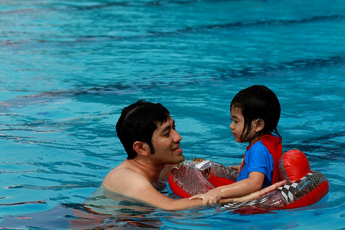 Father and daughter enjoying a swim using a floaty.