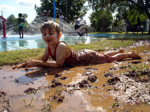 A young boy playing in the mud.