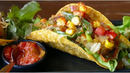 Image of a taco with corn and pico de gallo on top.