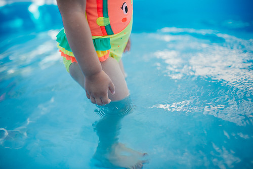 Small child standing in a shallow pool.