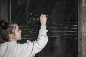 Young child drawing on chalkboard at music class.