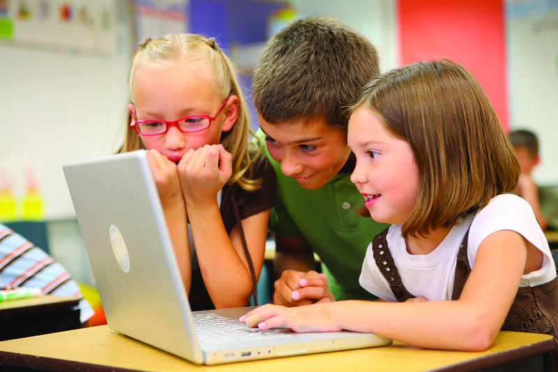 3 children at school learning on a laptop.