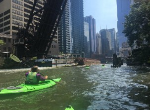 Man riding a kayak in Chicago, IL waterway.