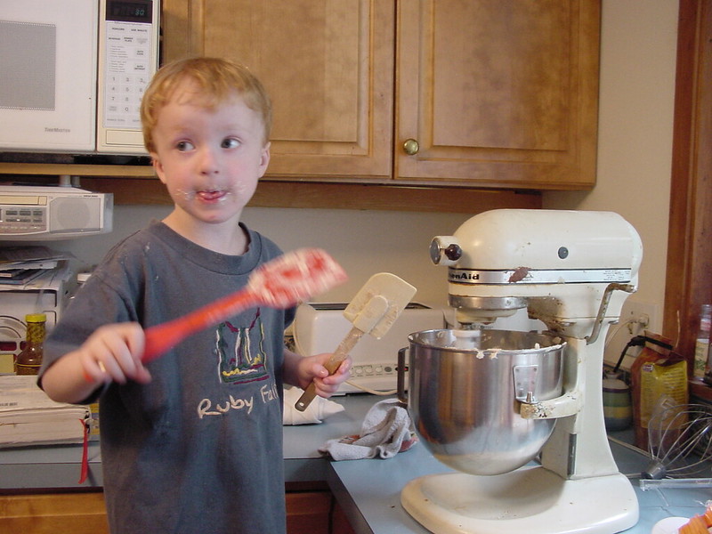 A child holding two spatulas in front of an electric mixer in Coppell, TX