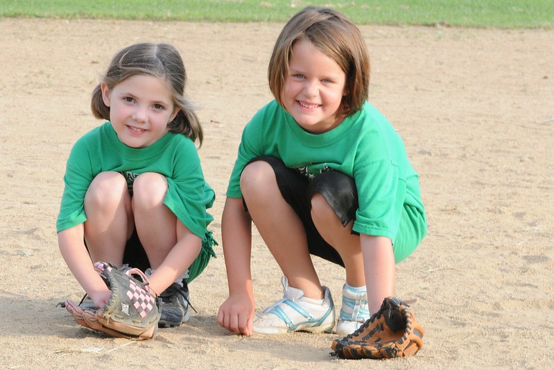 Two young girls with mitts on a baseball field in Frisco, TX