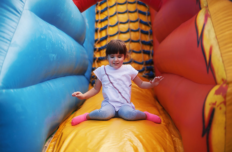 A small girl on an inflatable slide and trampoline in Thornton, CO