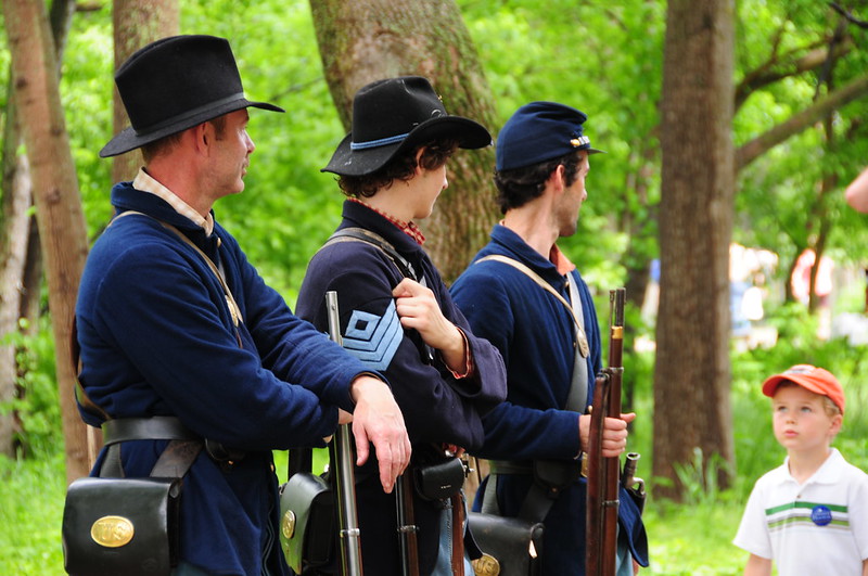 Three men performing a Civil War reenactment while a child looks on at Conner Prairie in Fishers, IN