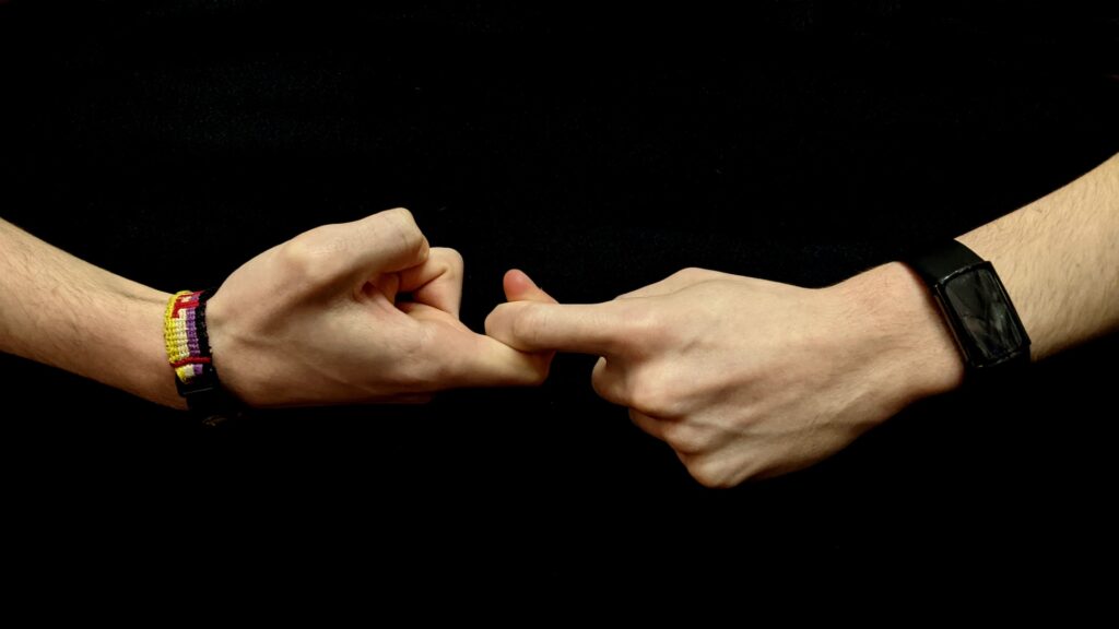 Two people holding hands by interlocking pointer fingers.