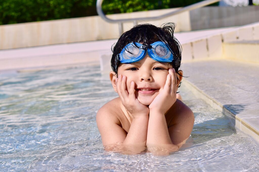 A child wearing googles in a pool at a mommy and me class in McKinney, TX
