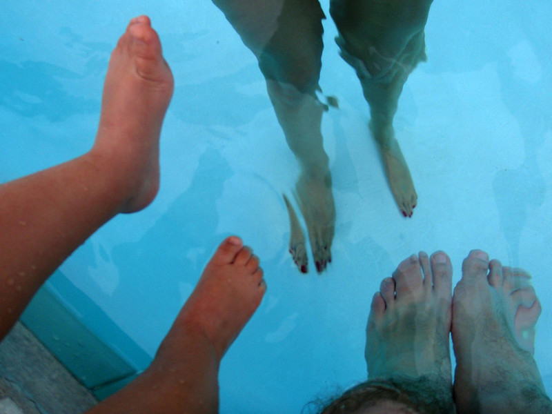 Three pairs of feet dangling in a swimming pool in Westmont, IL
