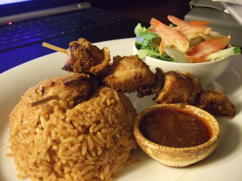 A dish of Ghanian food featuring rice, chicken kebab, and a salad at an African restaurant in Las Vegas.