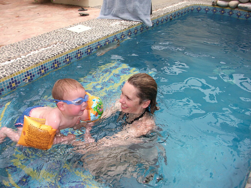 A mother in a pool with an infant wearing wings and goggles in McKinney, TX
