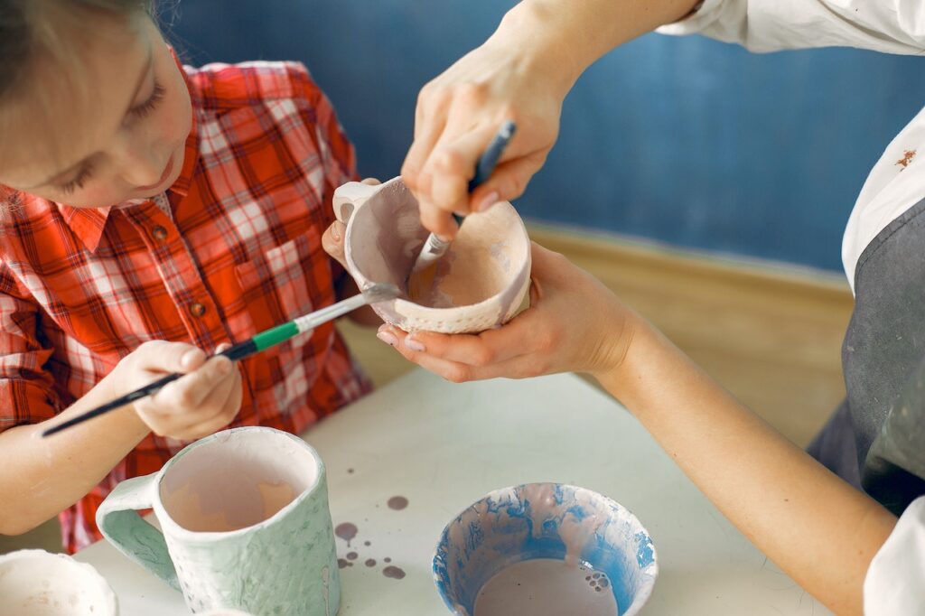 A teacher and a small girl painting an earthware bowl in Goodyear, AZ