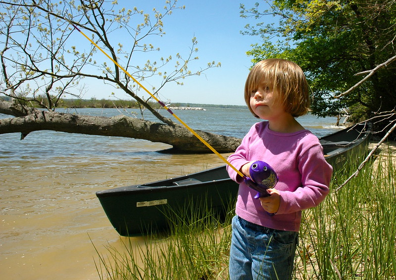 A small child with a fishing pole by a lake and a boat in Cedar Park, TX
