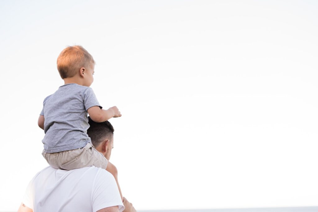 Man in a white shirt holding a small boy on his shoulders