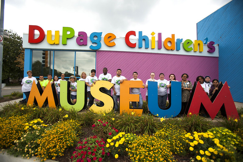 A large group of volunteers standing in front of the DuPage Children's Museum.