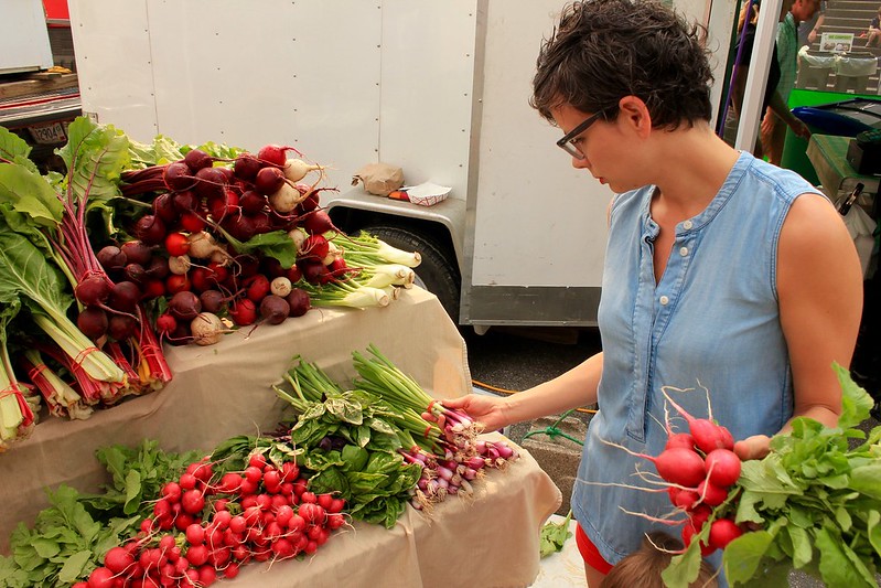 A woman picking out radishes from a farmers market near Colleyville, TX