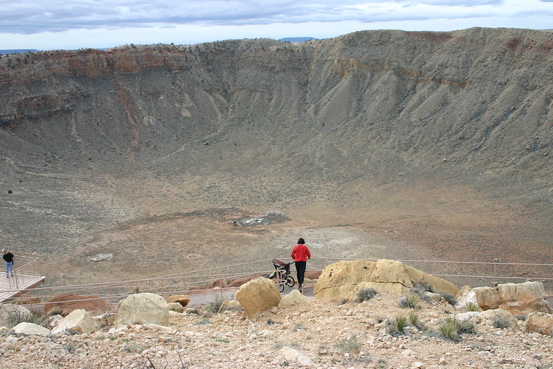 A person by a bicycle standing over Meteor Crater in Arizona