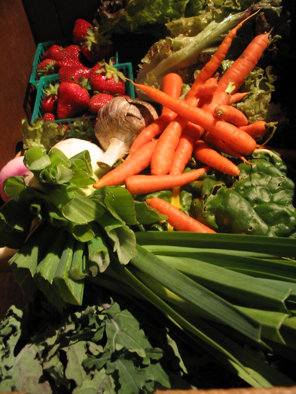 A box of vegetables including carrots, radishes, and lettuce.