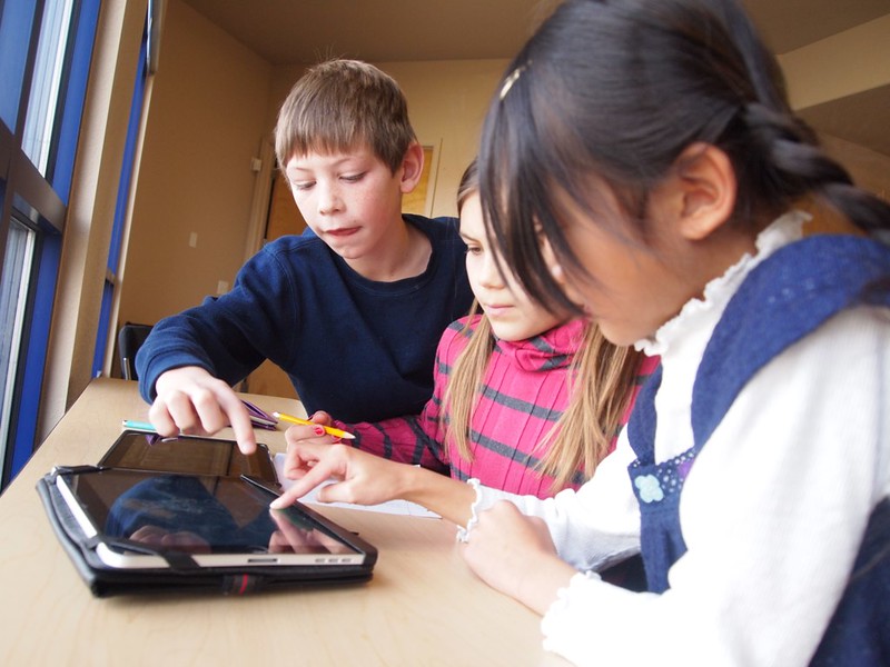 Three children taking a language course on an iPad in Georgia