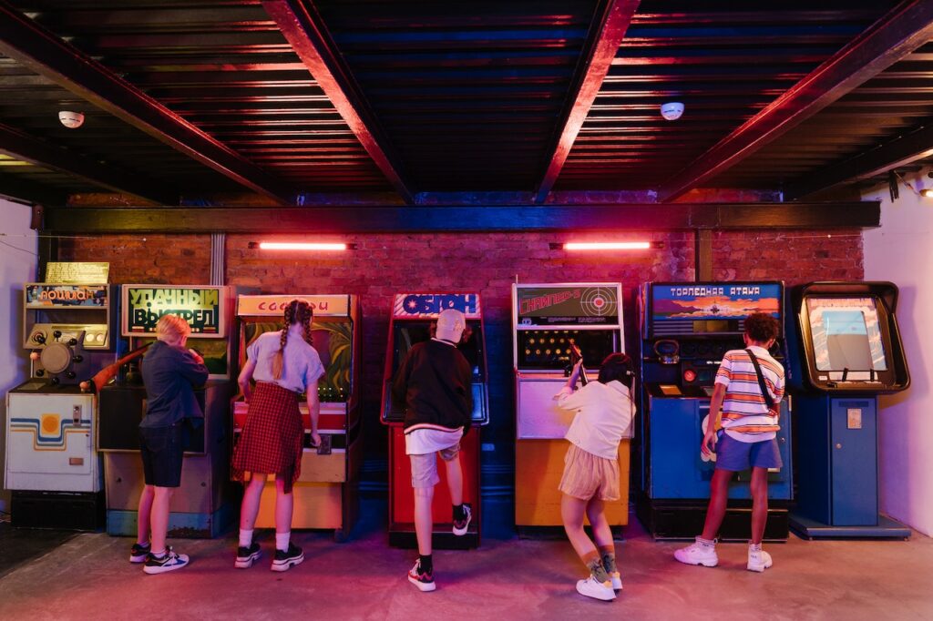 Kids standing in front of upright video games at an arcade.