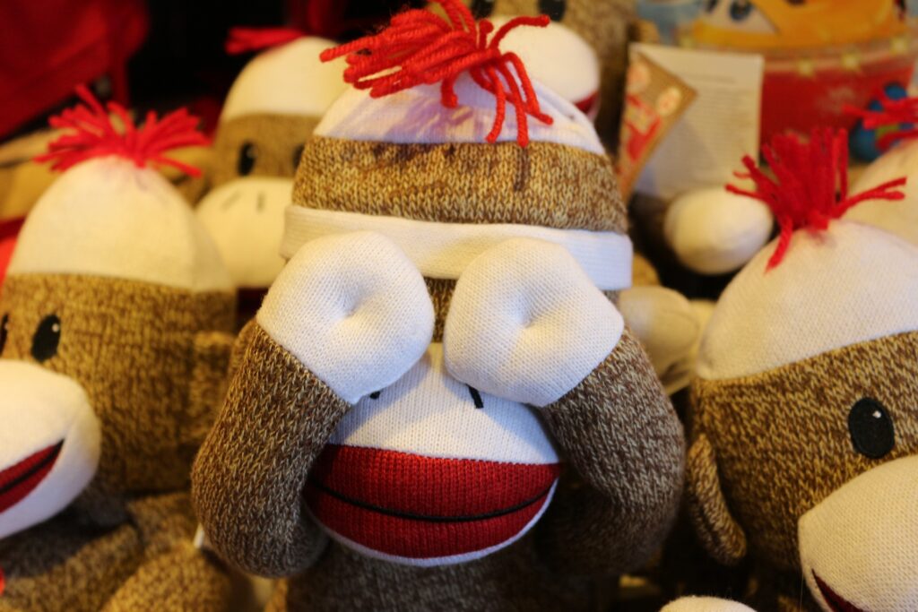 A sock monkey covering its eyes in front of other sock monkeys at a museum near Glenview, IL
