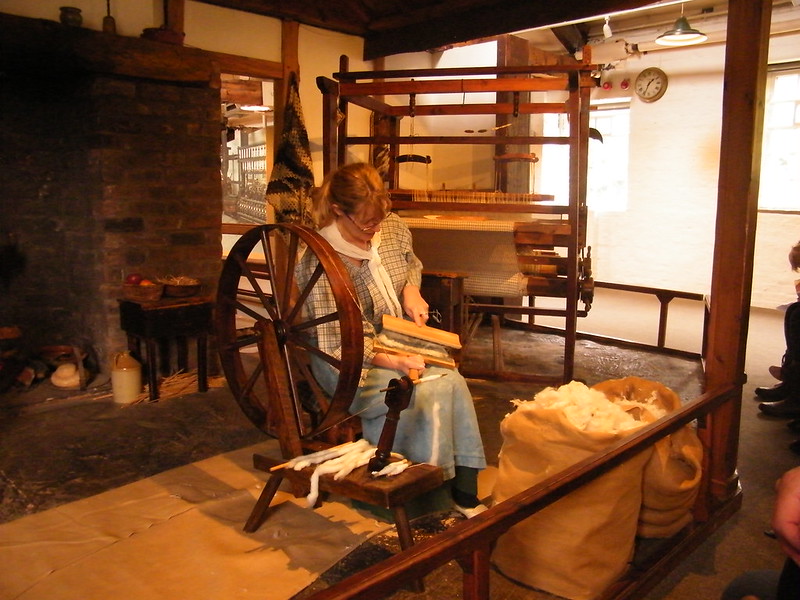 A woman working with a loom and a spinning wheel in Mason, OH