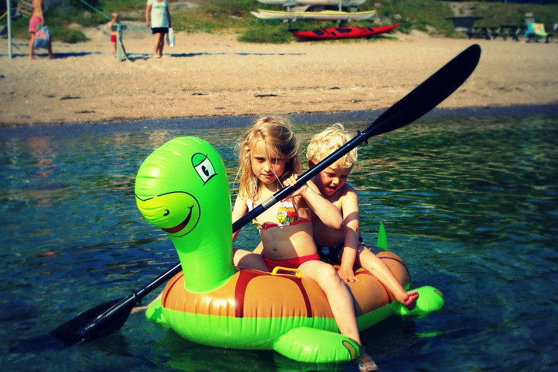 Two children paddling atop an inflatable turtle in Coppell, TX