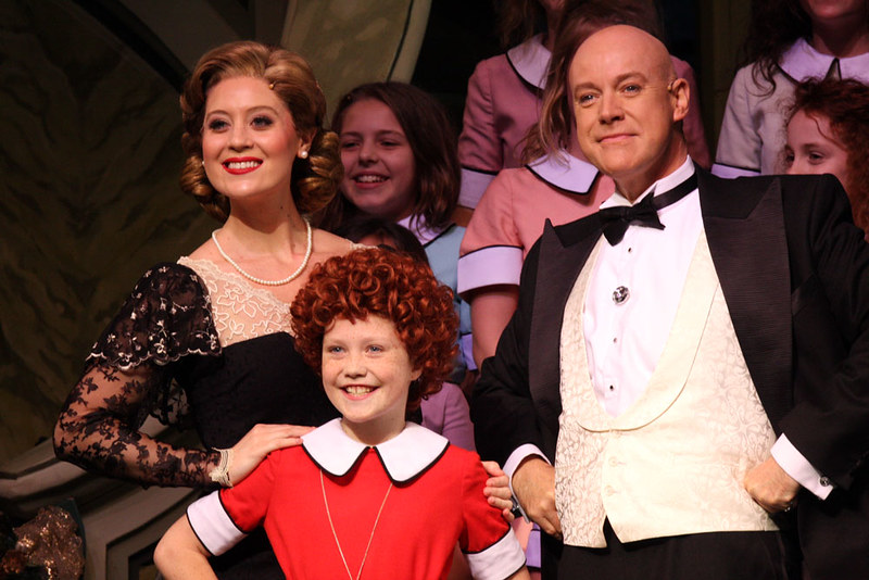 Three actors onstage during a production of Annie