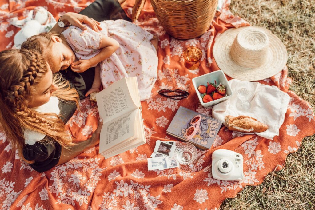 A woman reading to her child on a picnic blanket in The Woodlands, TX