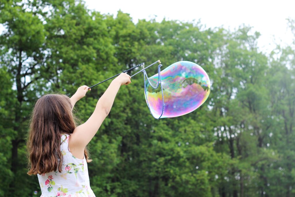 A girl making a large bubble with a wand at a park in Peoria, AZ