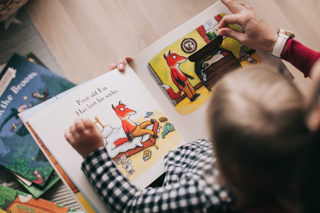 A person reading a children's book to a young child.