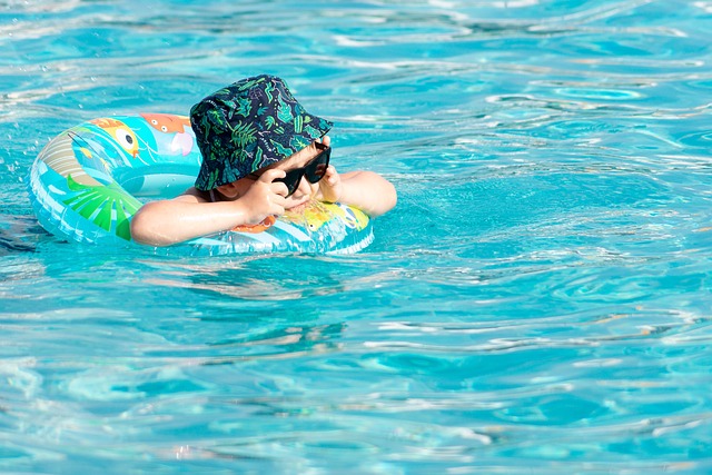 A child wearing sunglasses and a green bucket hat relaxing in an inner tube in a pool in Coppell, TX