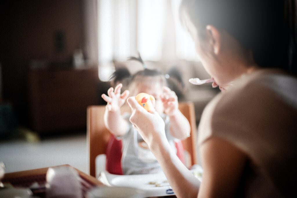 A mother holding a rubber duckie out for a child to grab