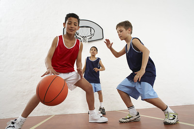 3 kids playing basketball in a gym