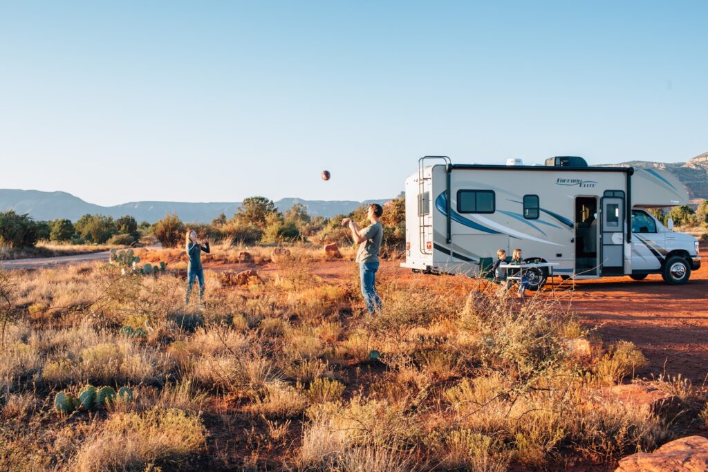 Two people playing catch with a football near an RV at a camping site in Gilbert, AZ