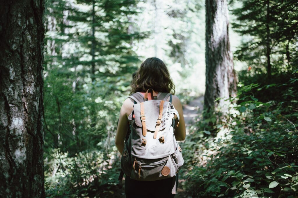 A woman with a backpack hiking through a forest in Georgia.