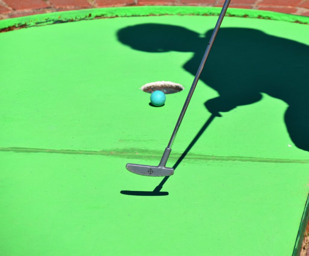 The shadow of a child putting on a miniature golf course in Oklahoma.