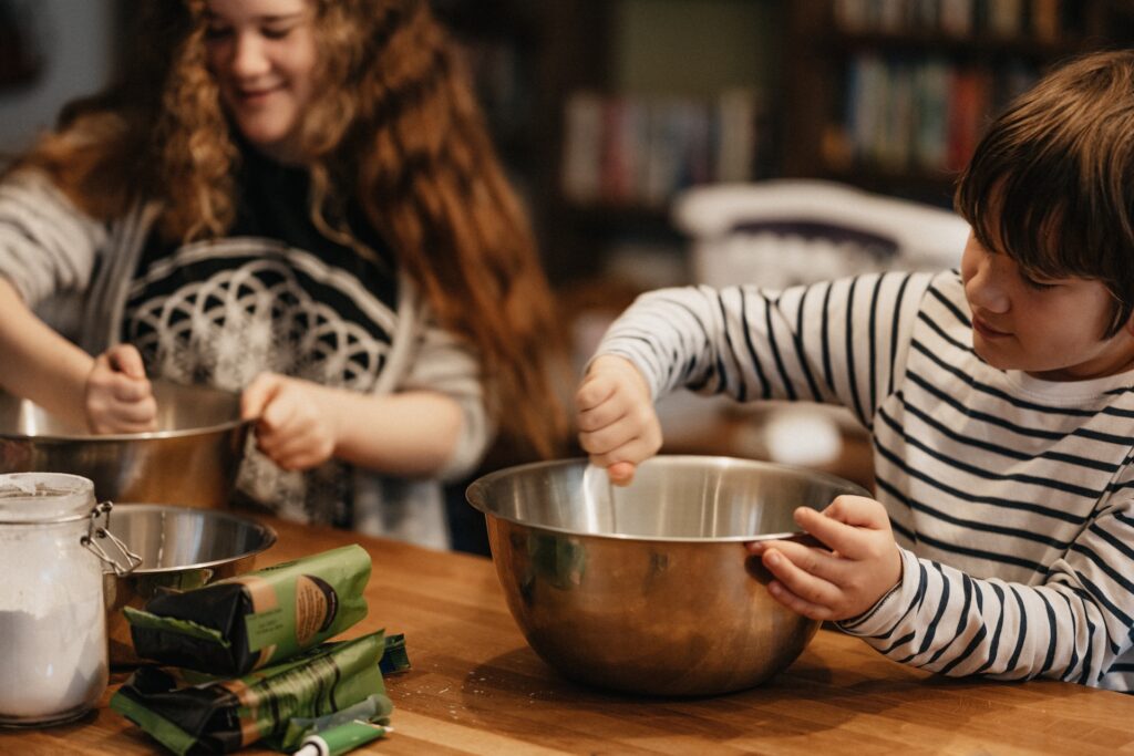 A child and a teen using mixing bowls at a cooking class in Plano, TX