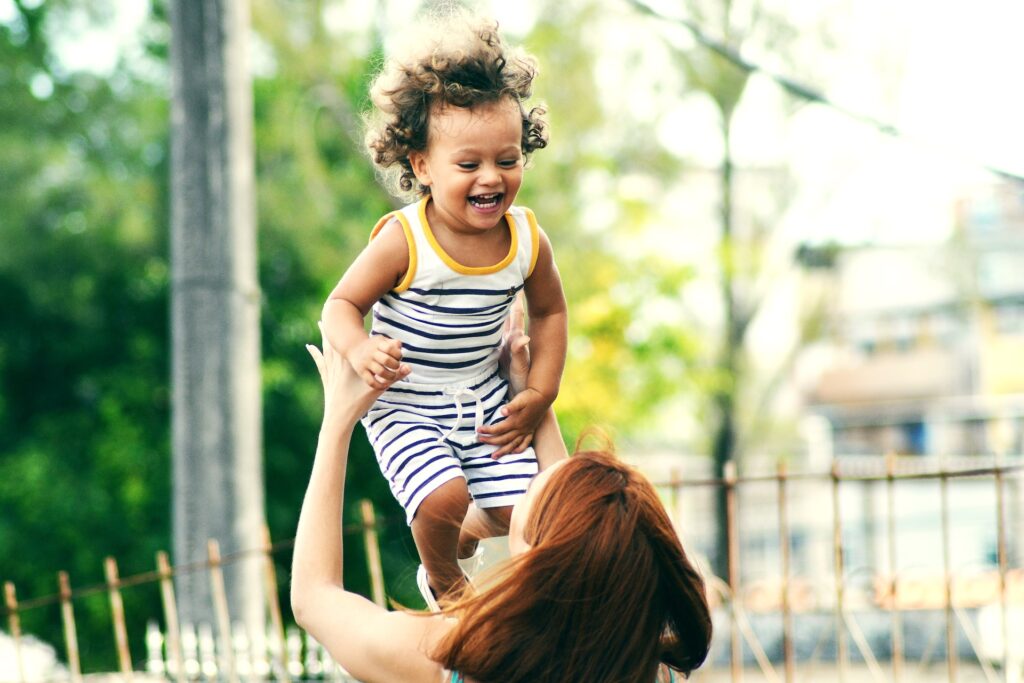 A mother holding a laughing child above her head at a Mommy & Me class in Marietta, GA